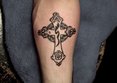 Black and gray tattoo of a stone cross with an Arab sign on it.