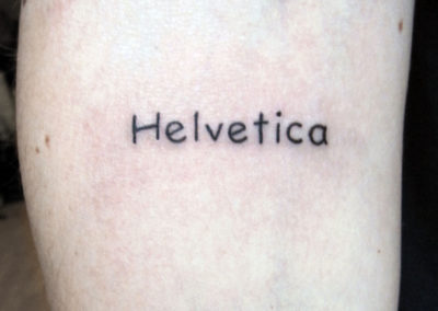 Tattoo of the word Helvetica in Comic Sans