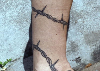 Tattoo of barbed wire on Rachels's leg. Punk style tattoo.