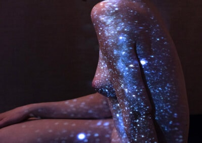 Artistic nude portrait of young female with the milky-way projected onto her.